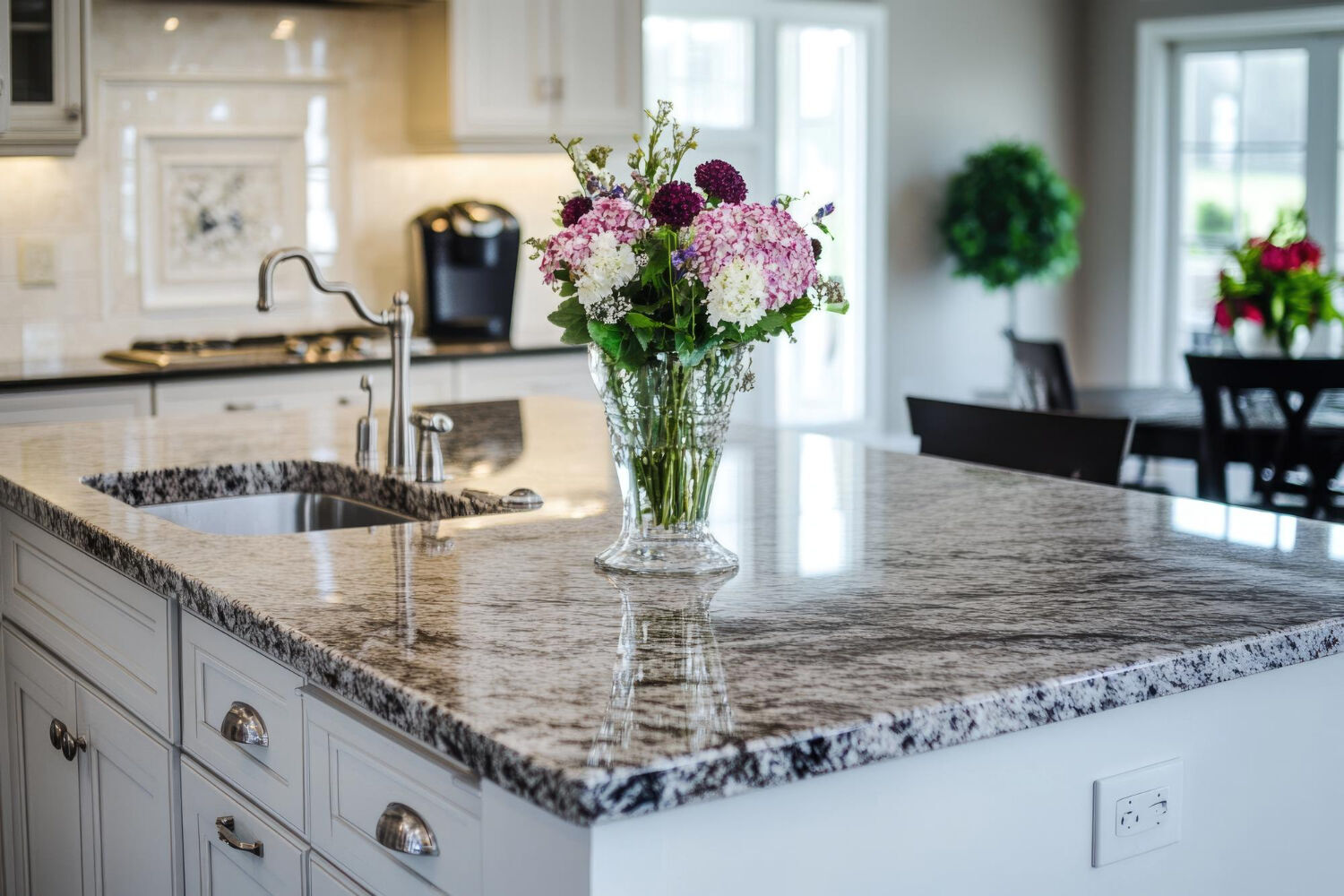 Modern kitchen with granite countertop island, built-in sink, and flower vase