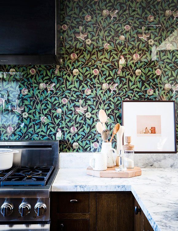 Kitchen with floral tile backsplash, marble countertop, and stainless steel stove