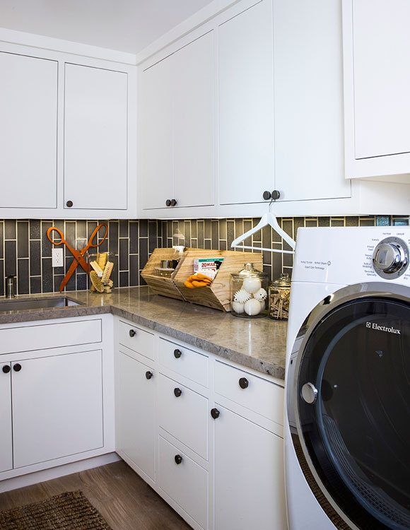 Laundry room with white cabinets, gray countertop, and dark subway tile backsplash