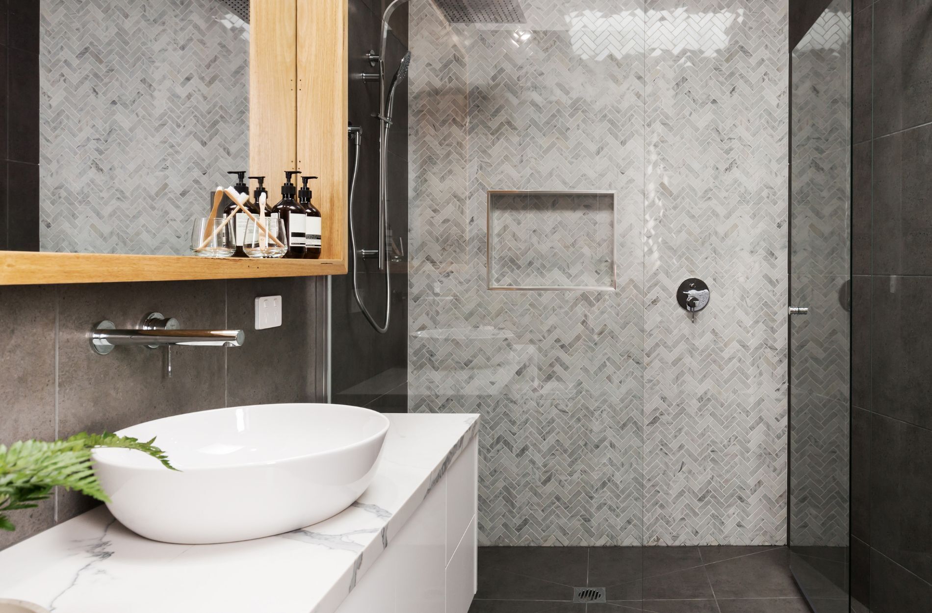 Bathroom with herringbone tile shower wall, white countertop, and vessel sink
