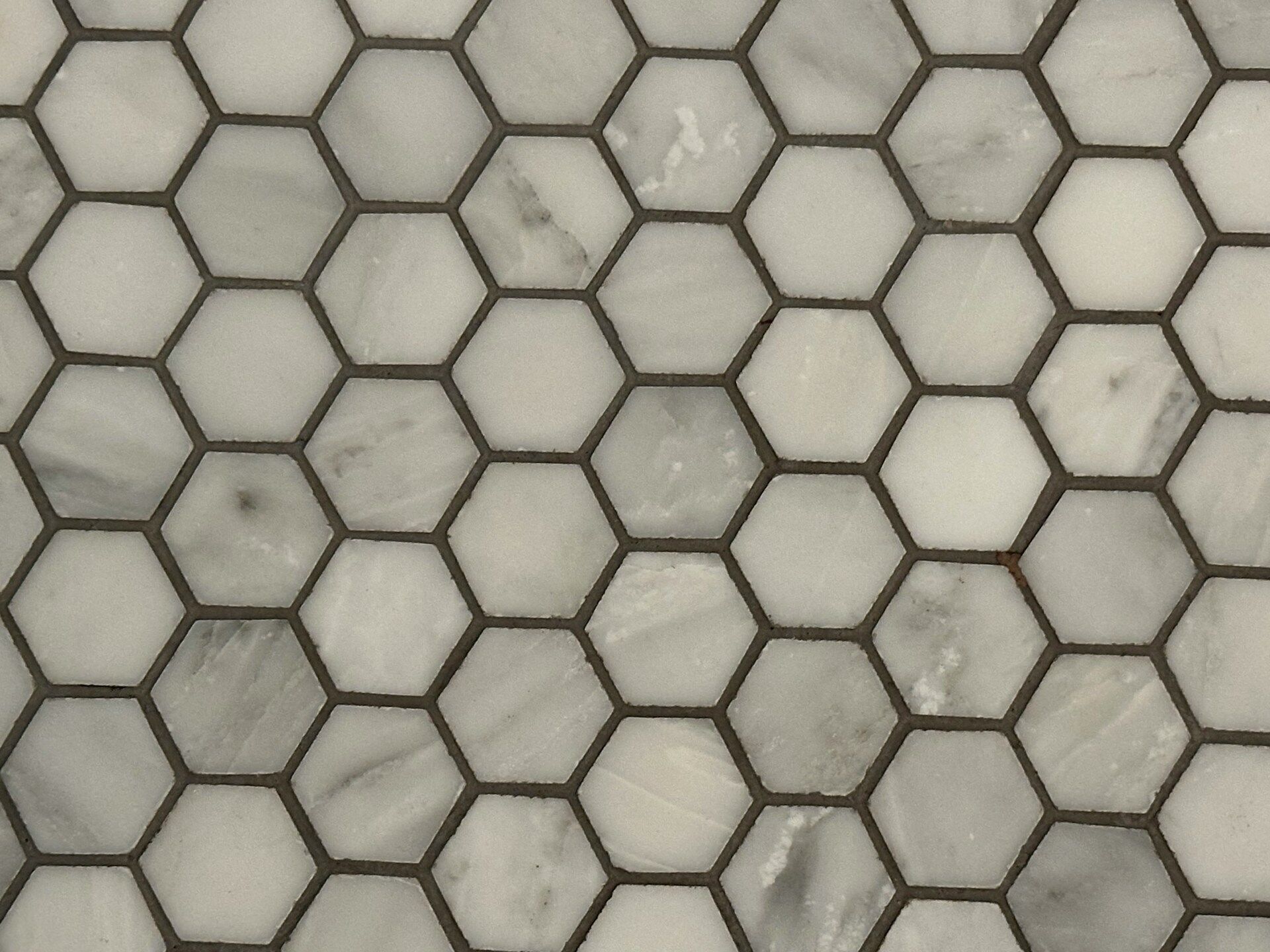Close-up of hexagonal marble tiles with grout lines, showing a classic pattern