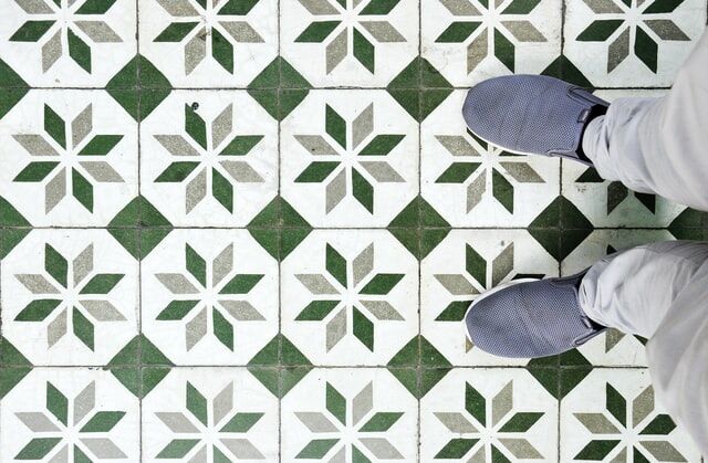 Top-down view of green and white geometric star pattern tiles with sneakers visible