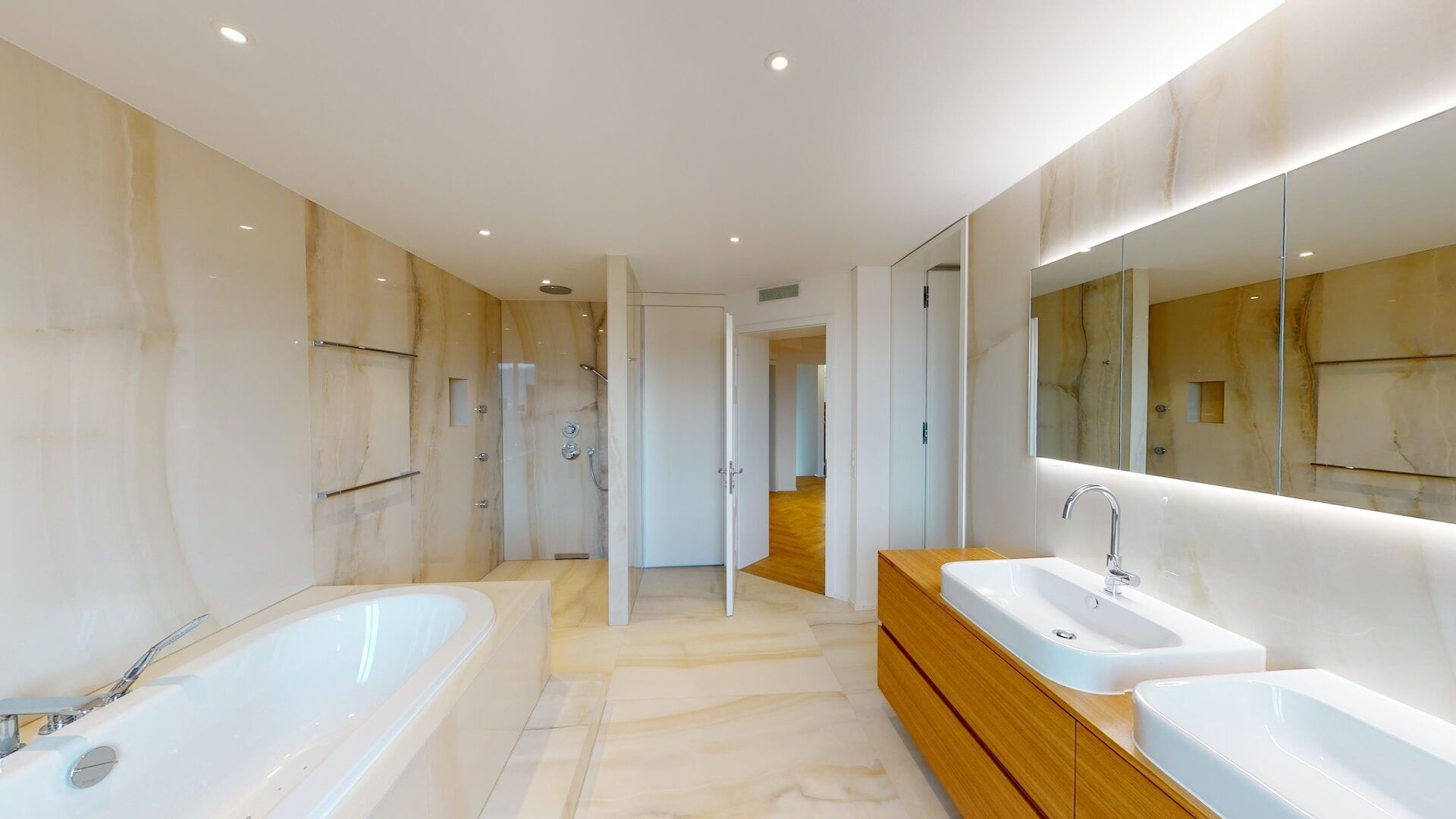 Modern bathroom with marble walls and floor, freestanding tub, and double vanity with vessel sinks