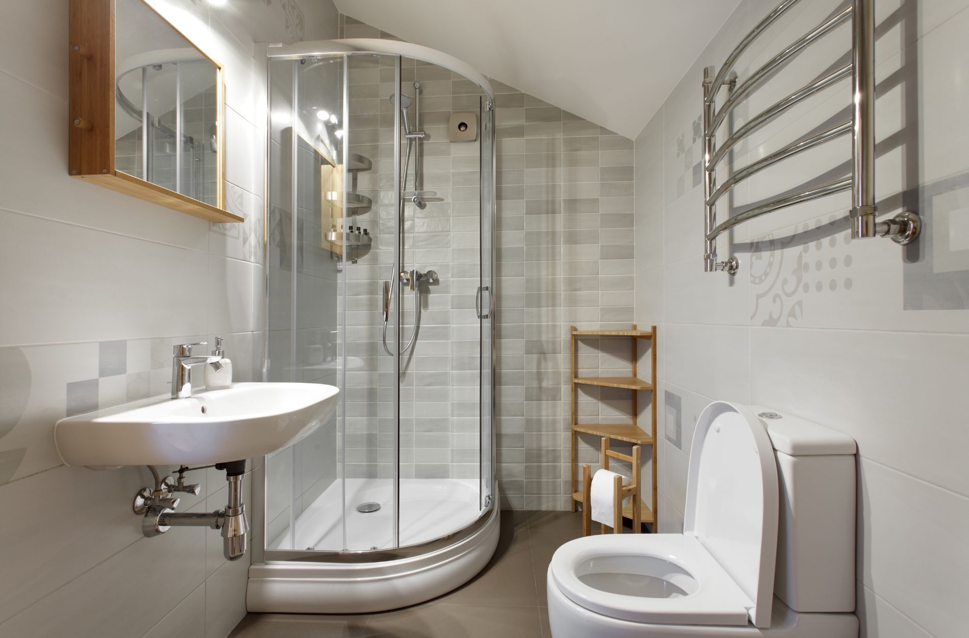 Small bathroom with corner shower, wall-mounted sink, and light gray tiles