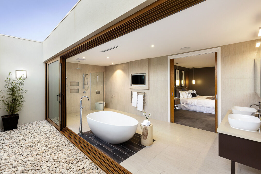 Modern bathroom with freestanding tub, dual sinks, and walk-in shower, connected to a bedroom