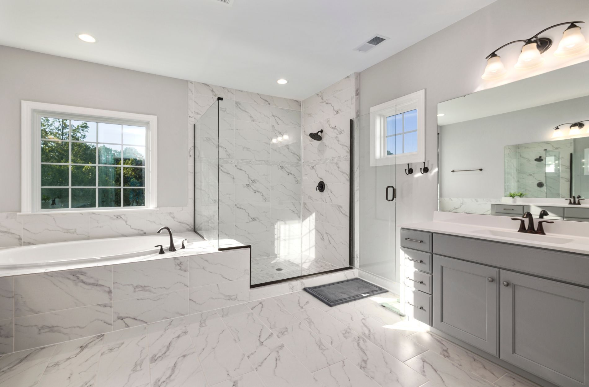 Modern bathroom with marble tile, walk-in shower, and bathtub