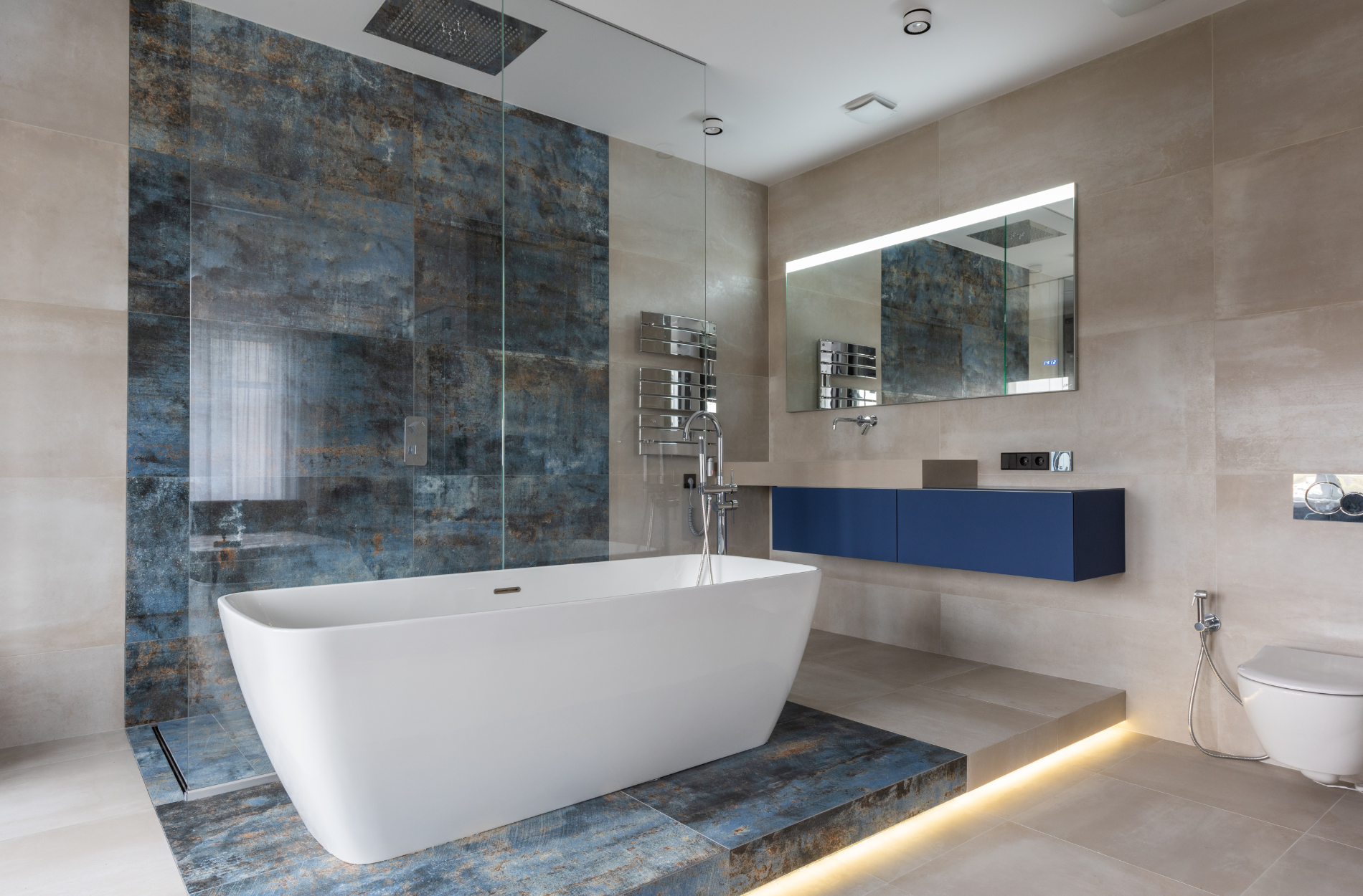 Modern bathroom with freestanding tub, blue accent tiles, and floating vanity