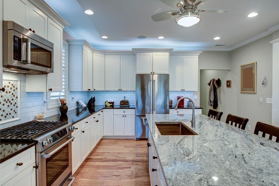 Modern kitchen with granite island, white cabinets, and stainless steel appliances
