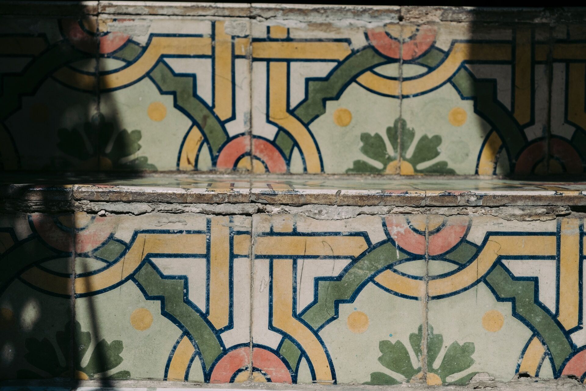 Close-up of decorative tiles on a staircase with geometric and floral patterns in various colors