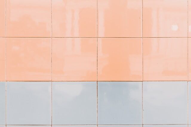 Wall with peach and light gray square tiles arranged in a simple pattern