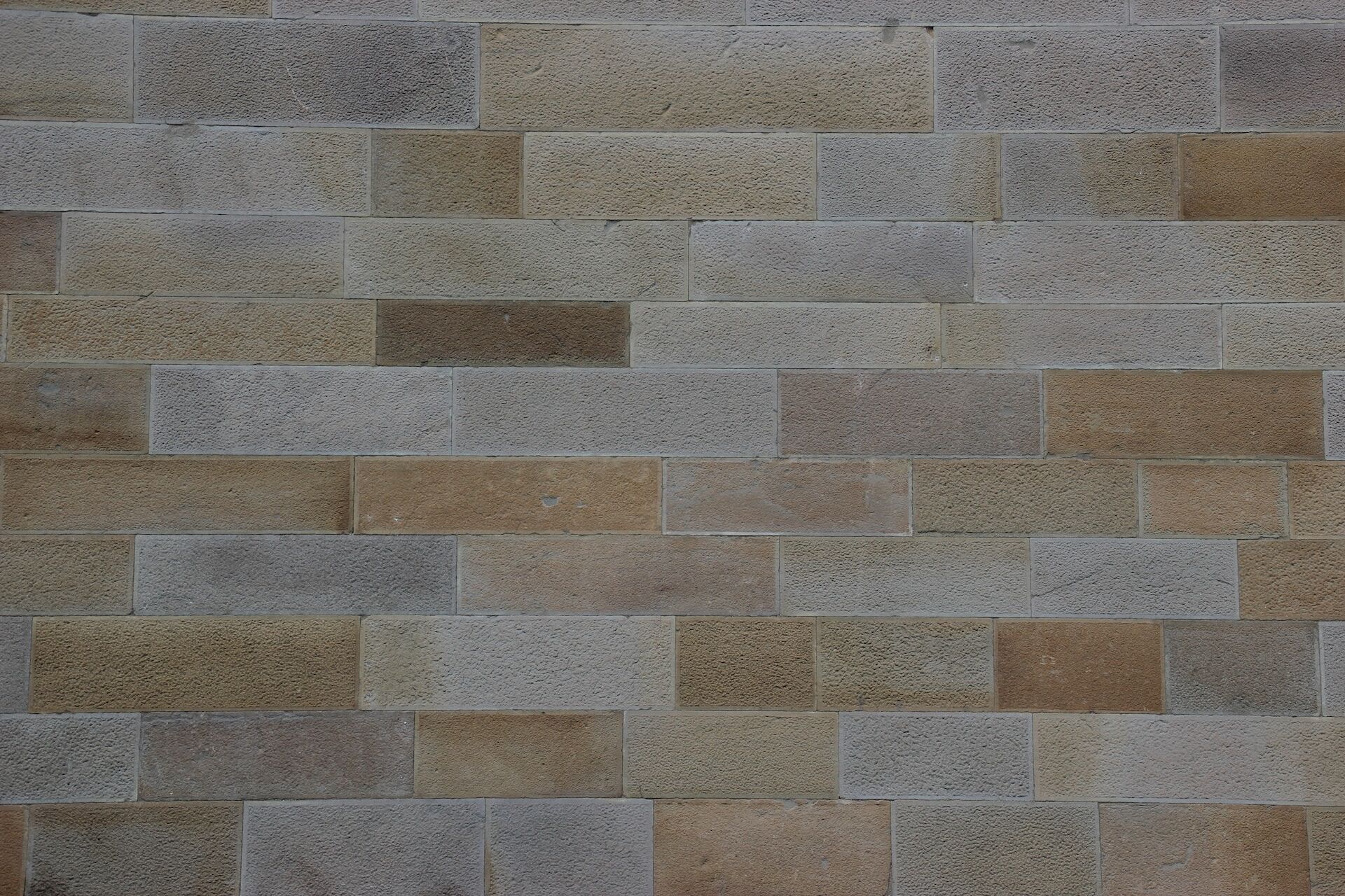 Close-up of a textured stone wall with rectangular tiles in shades of brown and gray