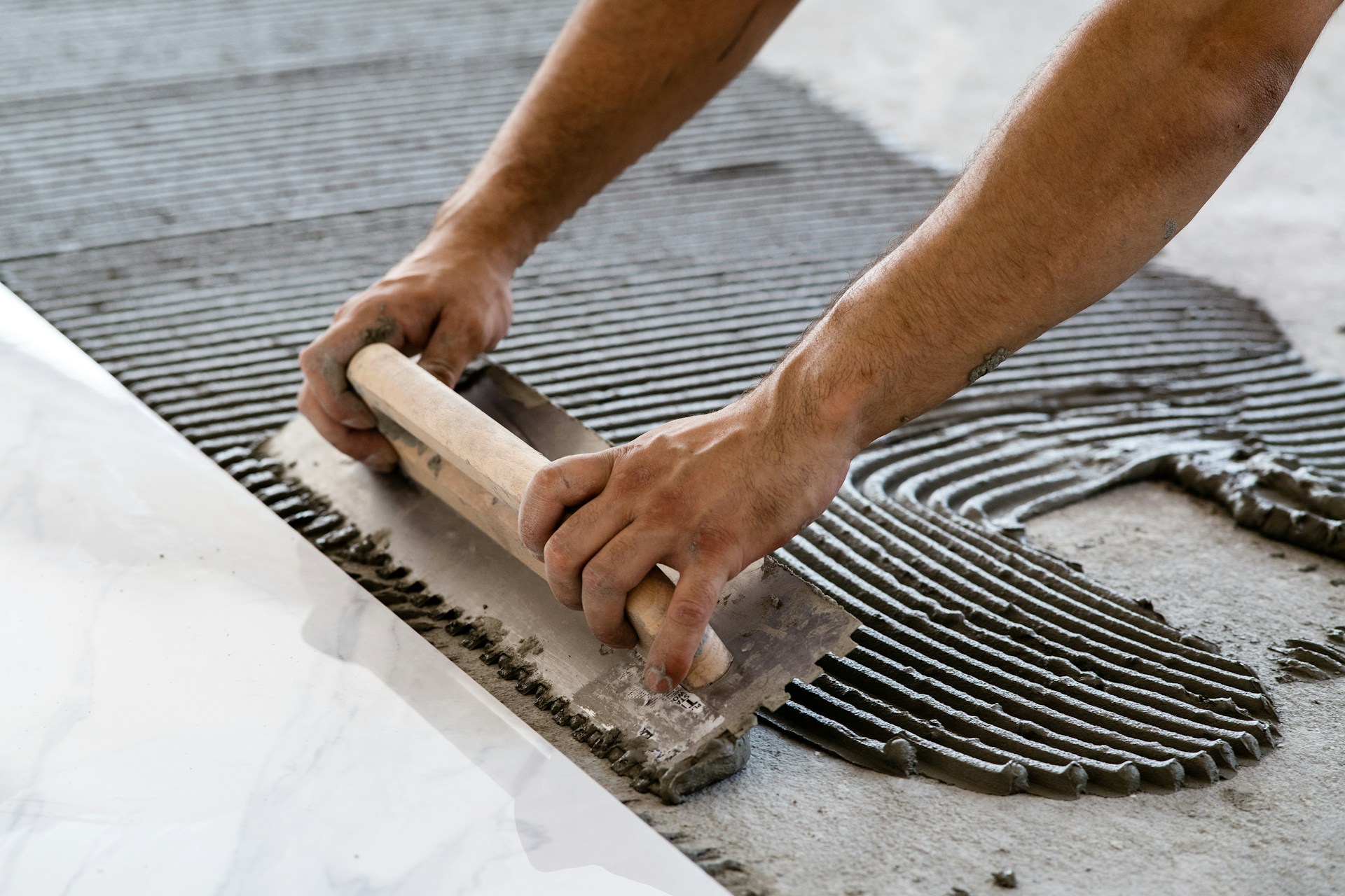 Person using a trowel to spread adhesive on a floor for tile installation
