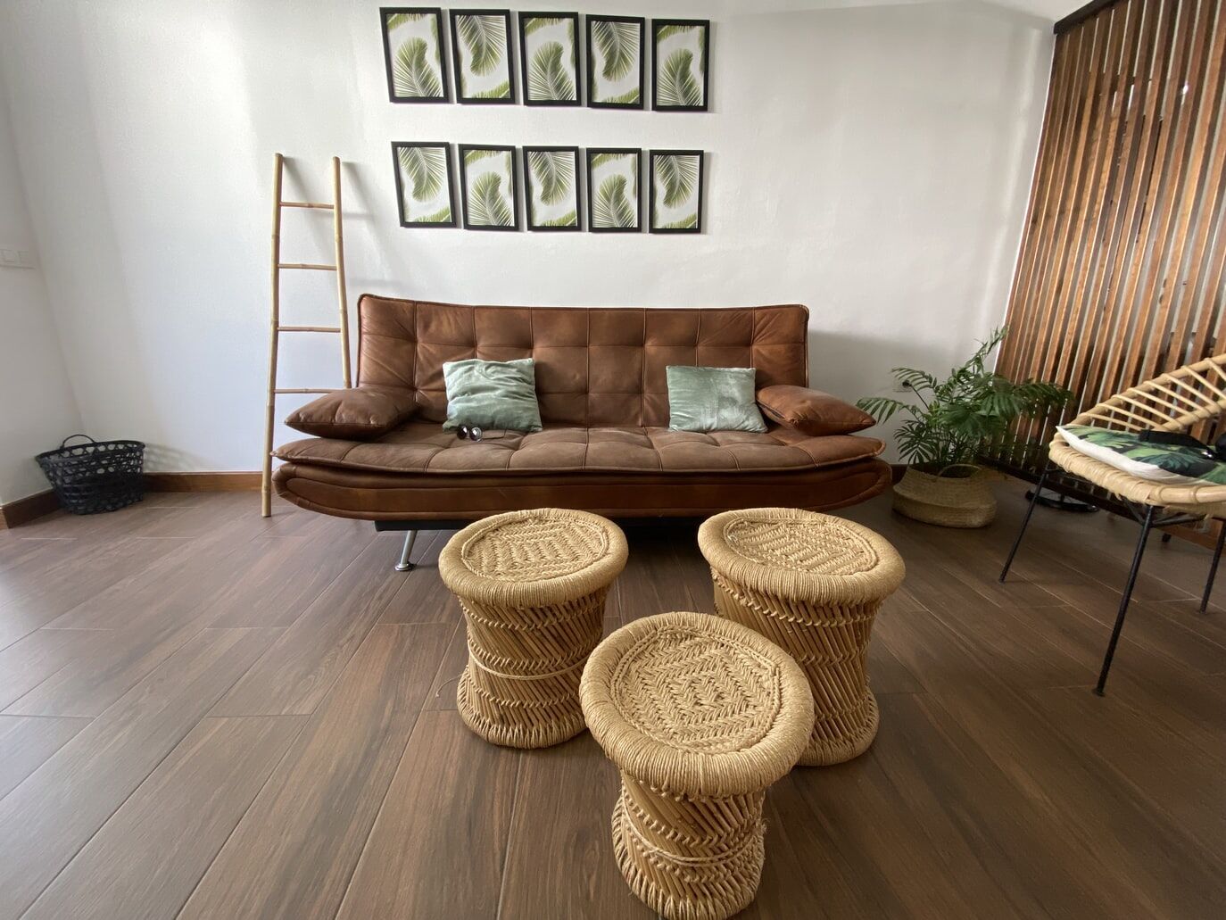 Living room featuring brown sofa, wicker stools, and wood-look vinyl flooring with wall art