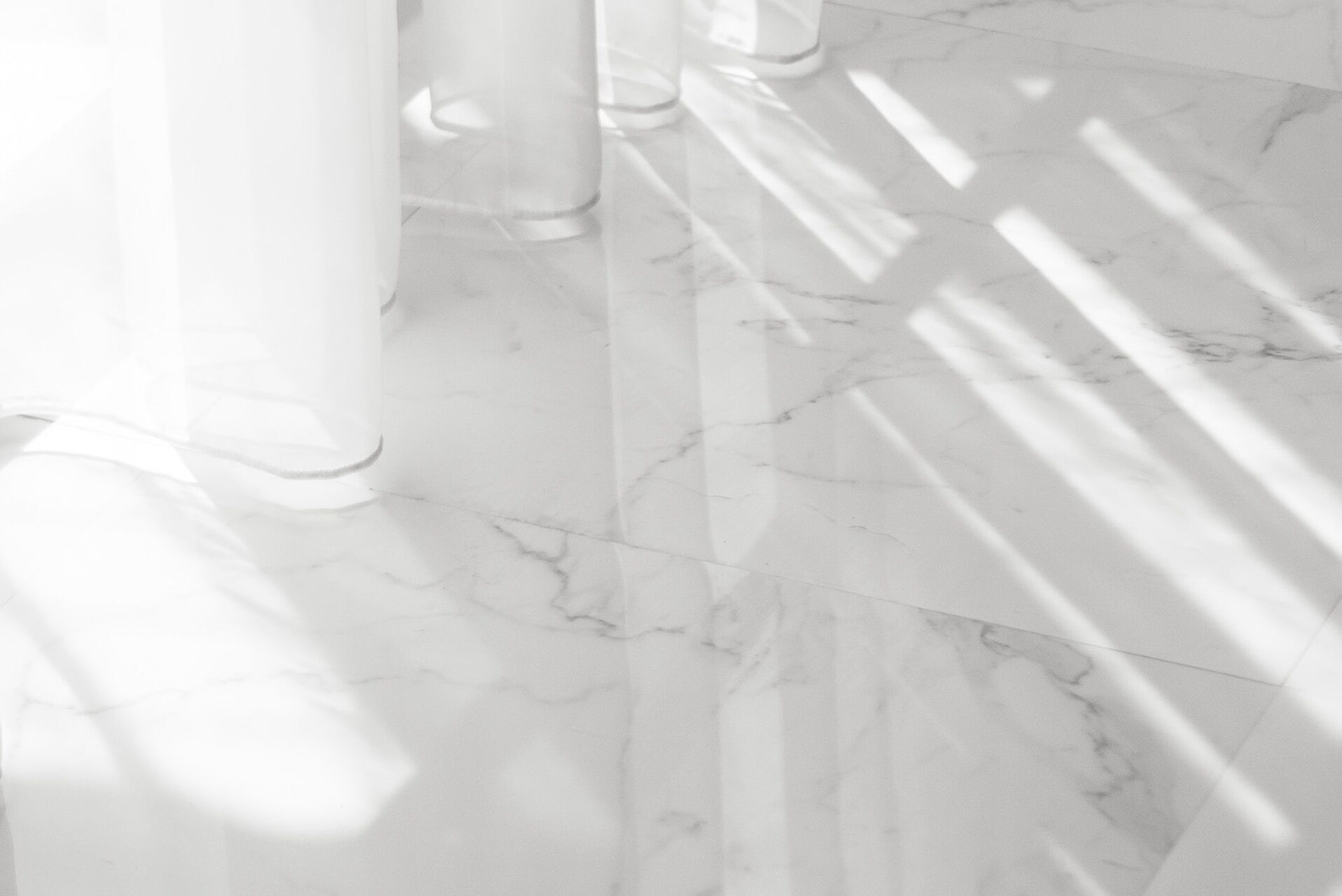 Close-up of polished white marble floor with light and shadows from a window