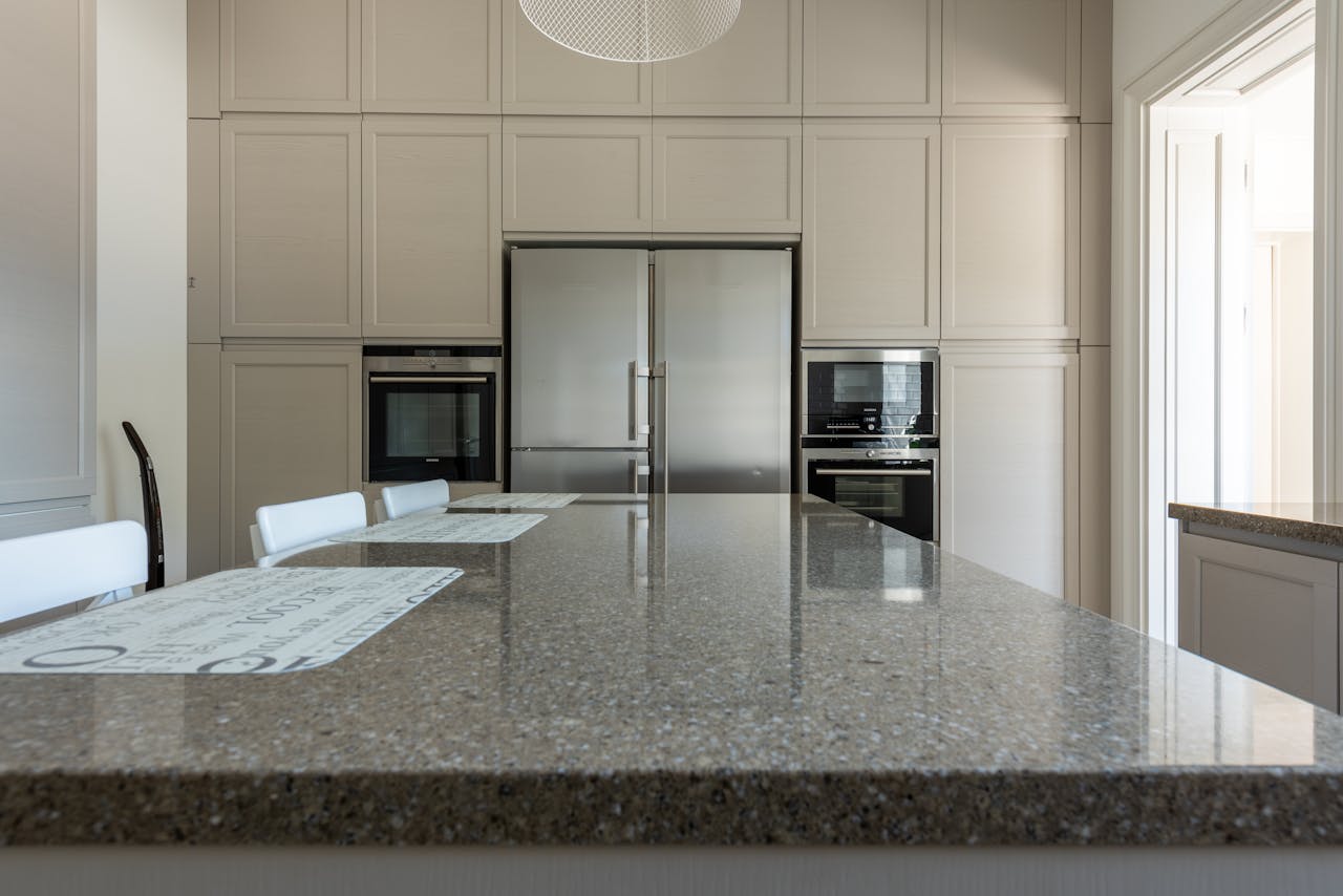 Modern kitchen with polished granite countertop, stainless steel appliances, and light cabinetry