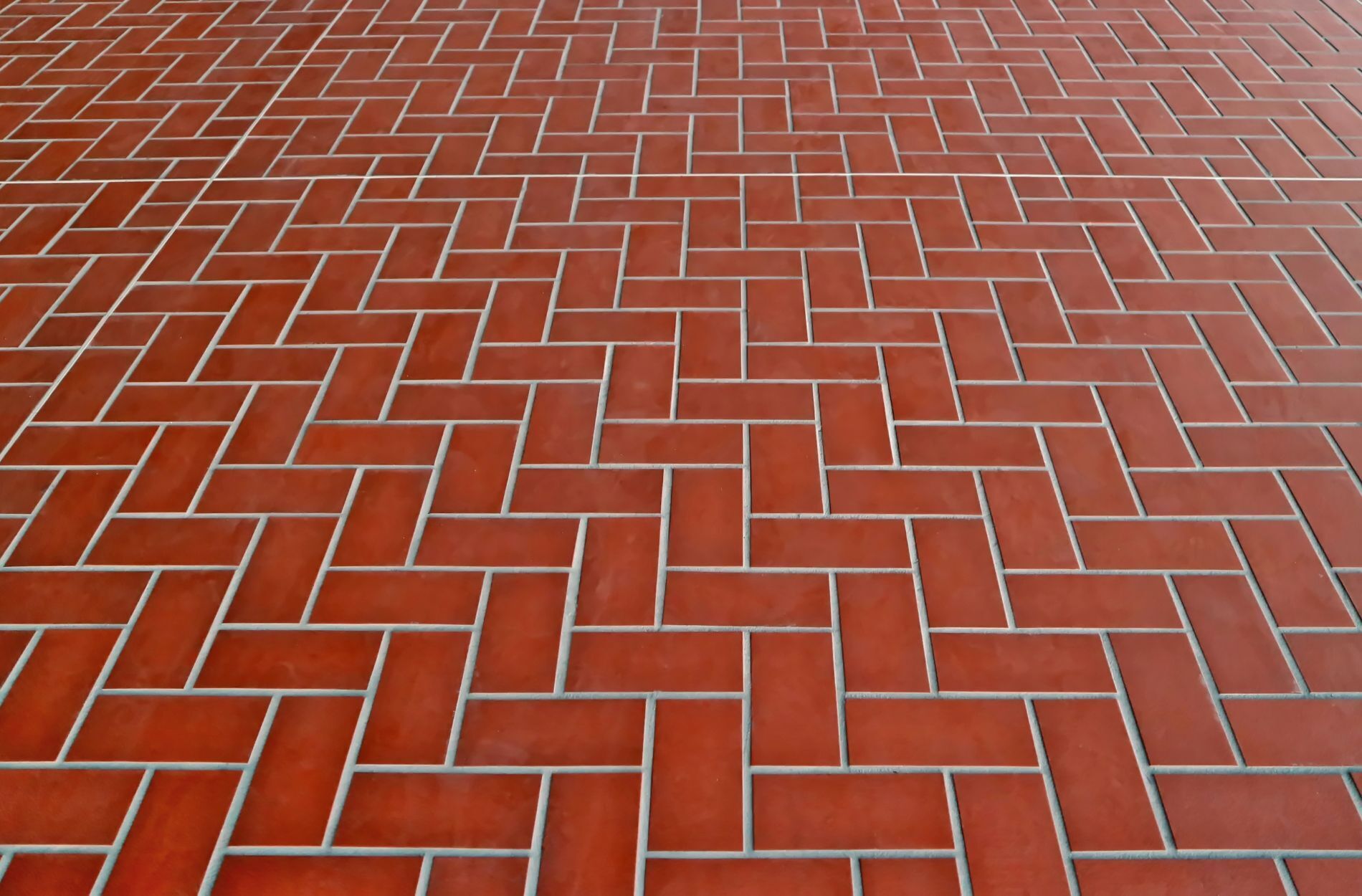 Close-up of red herringbone tile floor pattern with grout lines visible