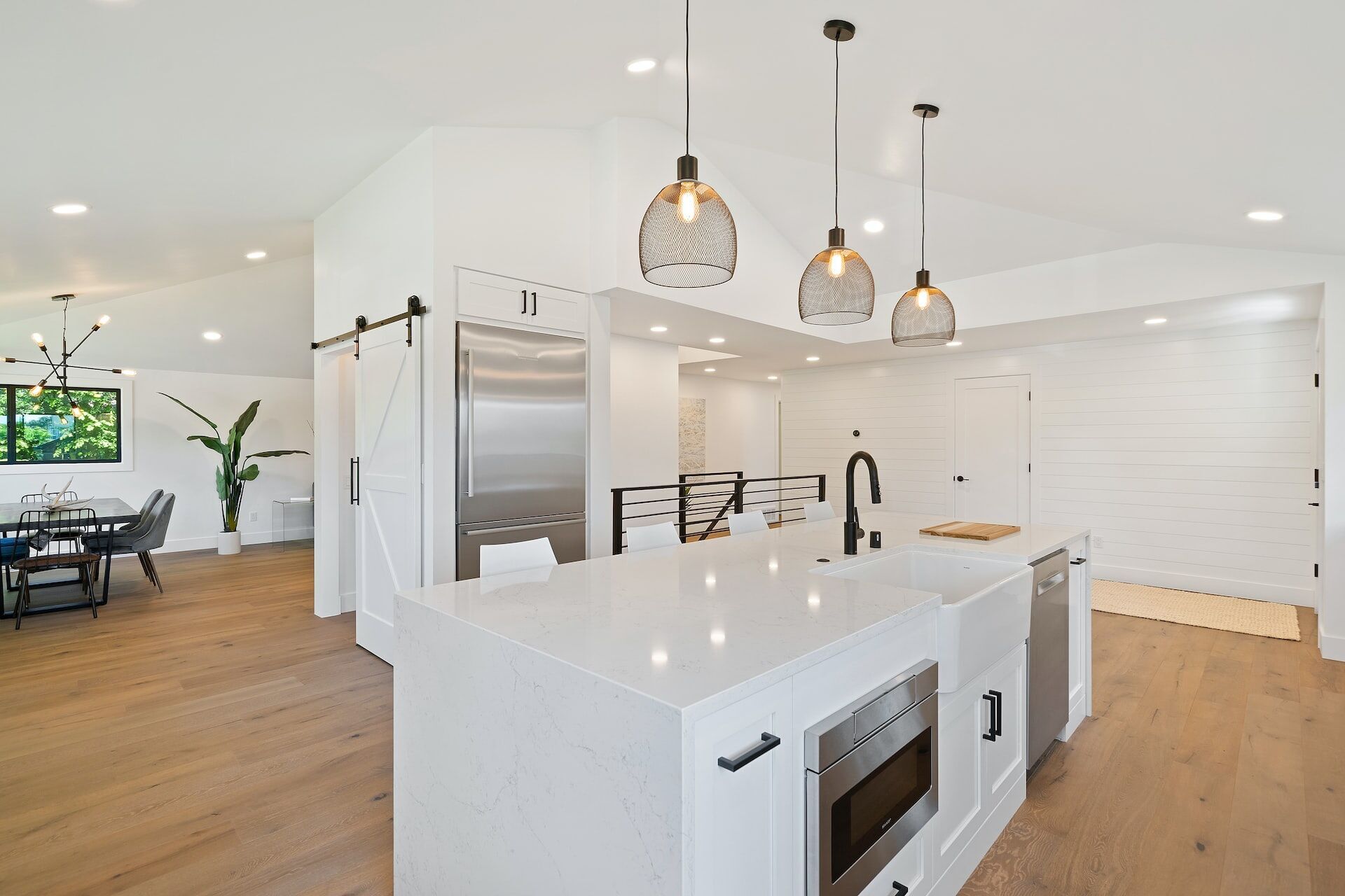Modern kitchen with white quartz island, pendant lights, and stainless steel appliances