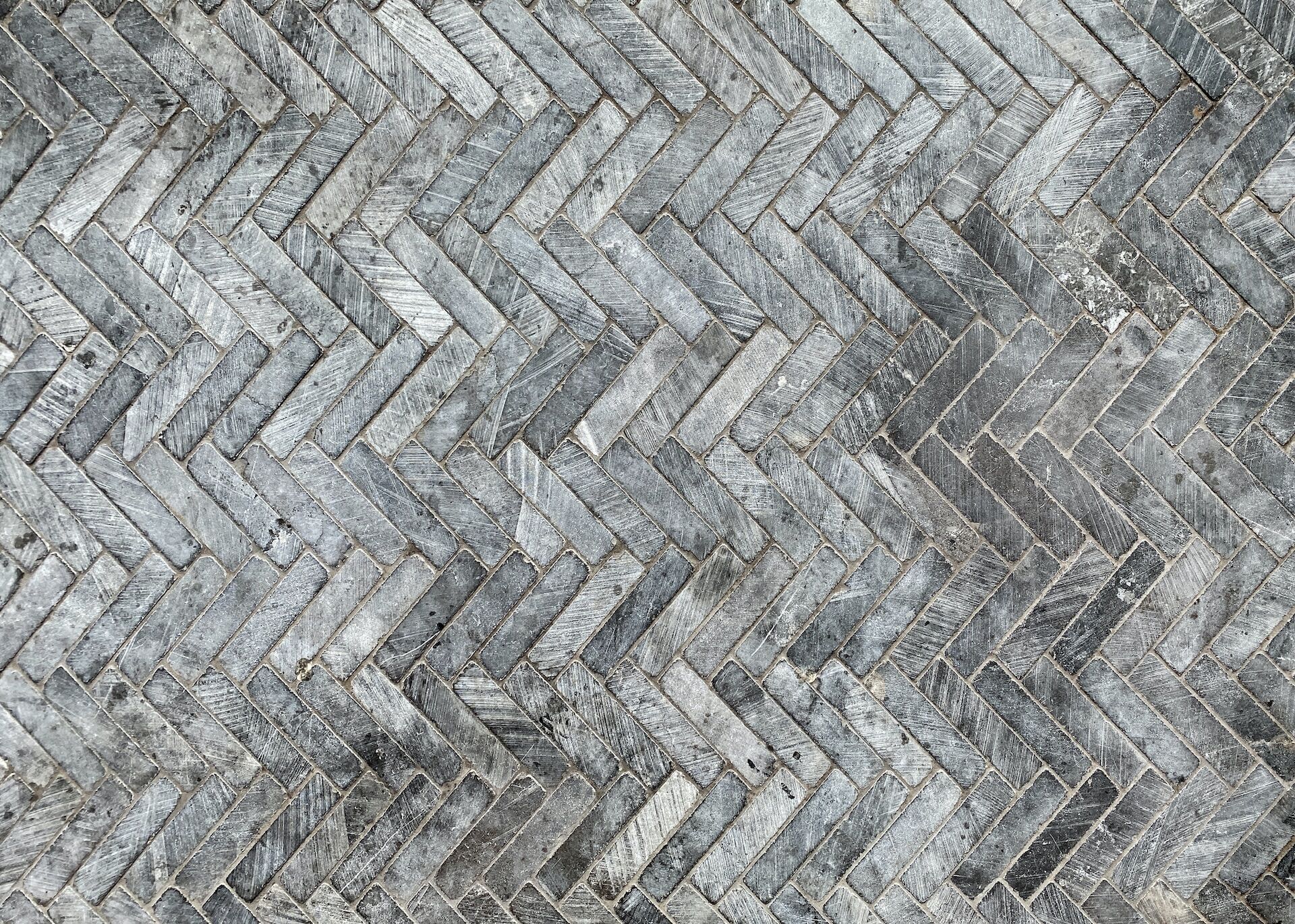 Close-up of gray stone tiles arranged in a herringbone pattern, highlighting texture and detail