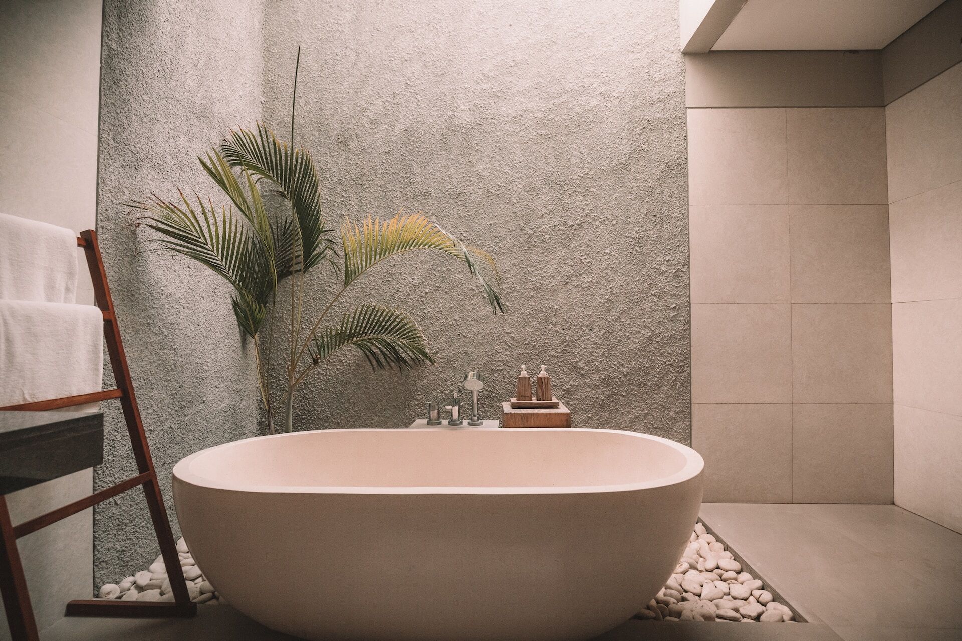 Modern bathroom with a freestanding tub, textured wall, and decorative plant