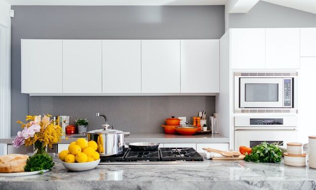 Modern kitchen featuring a marble countertop, white cabinets, and colorful kitchenware