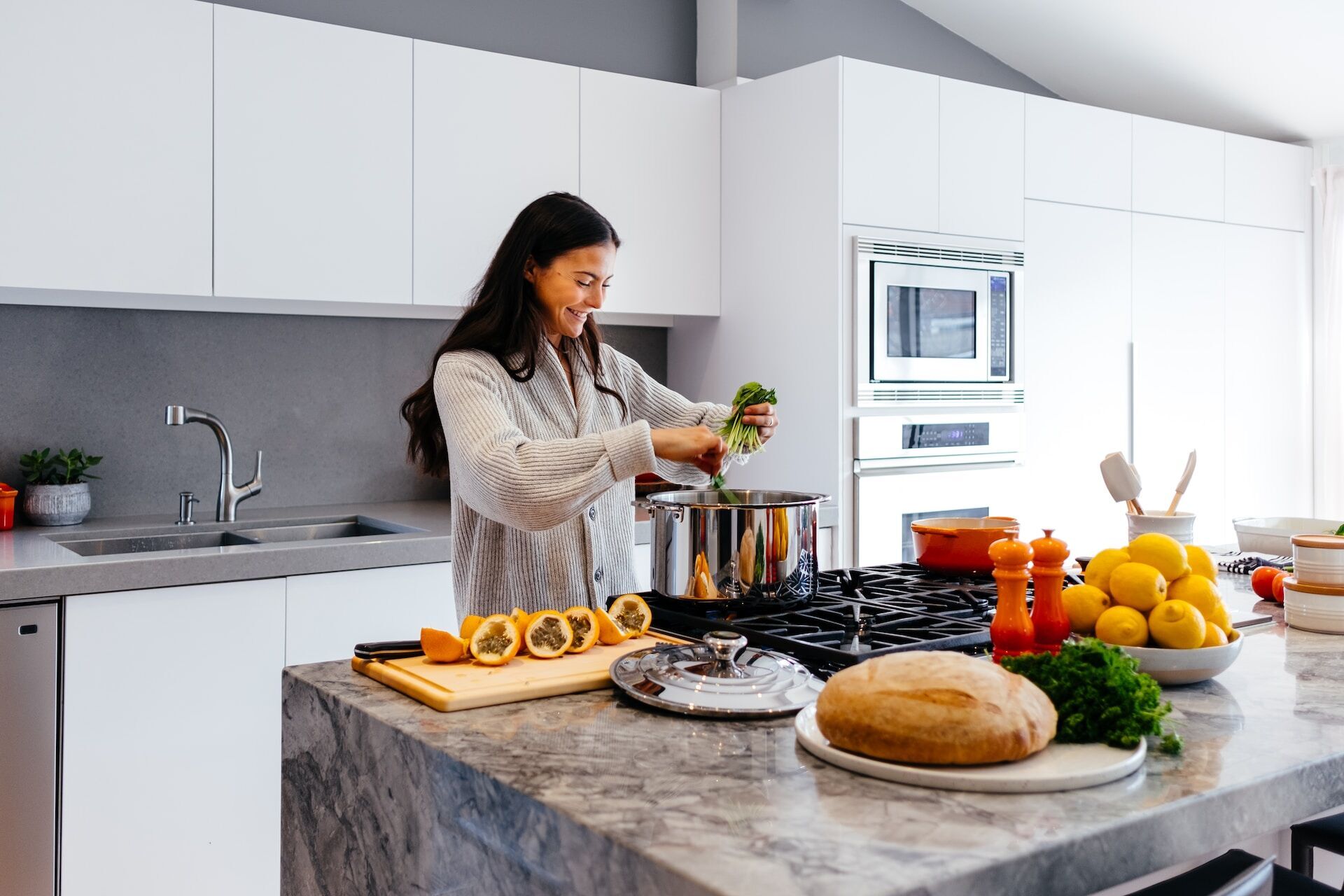 Woman cooking in a modern kitchen with granite countertop and white cabinets