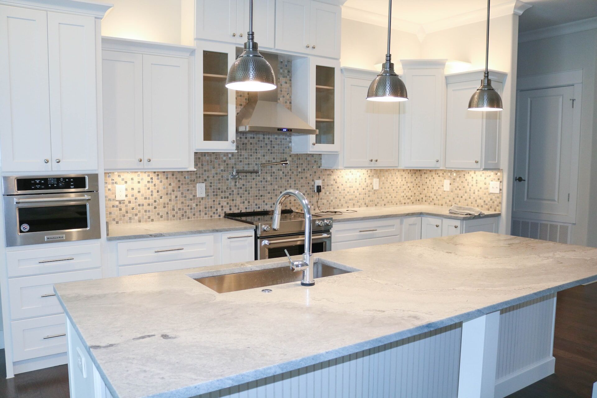 Modern kitchen with granite countertop island, white cabinets, and stainless steel appliances