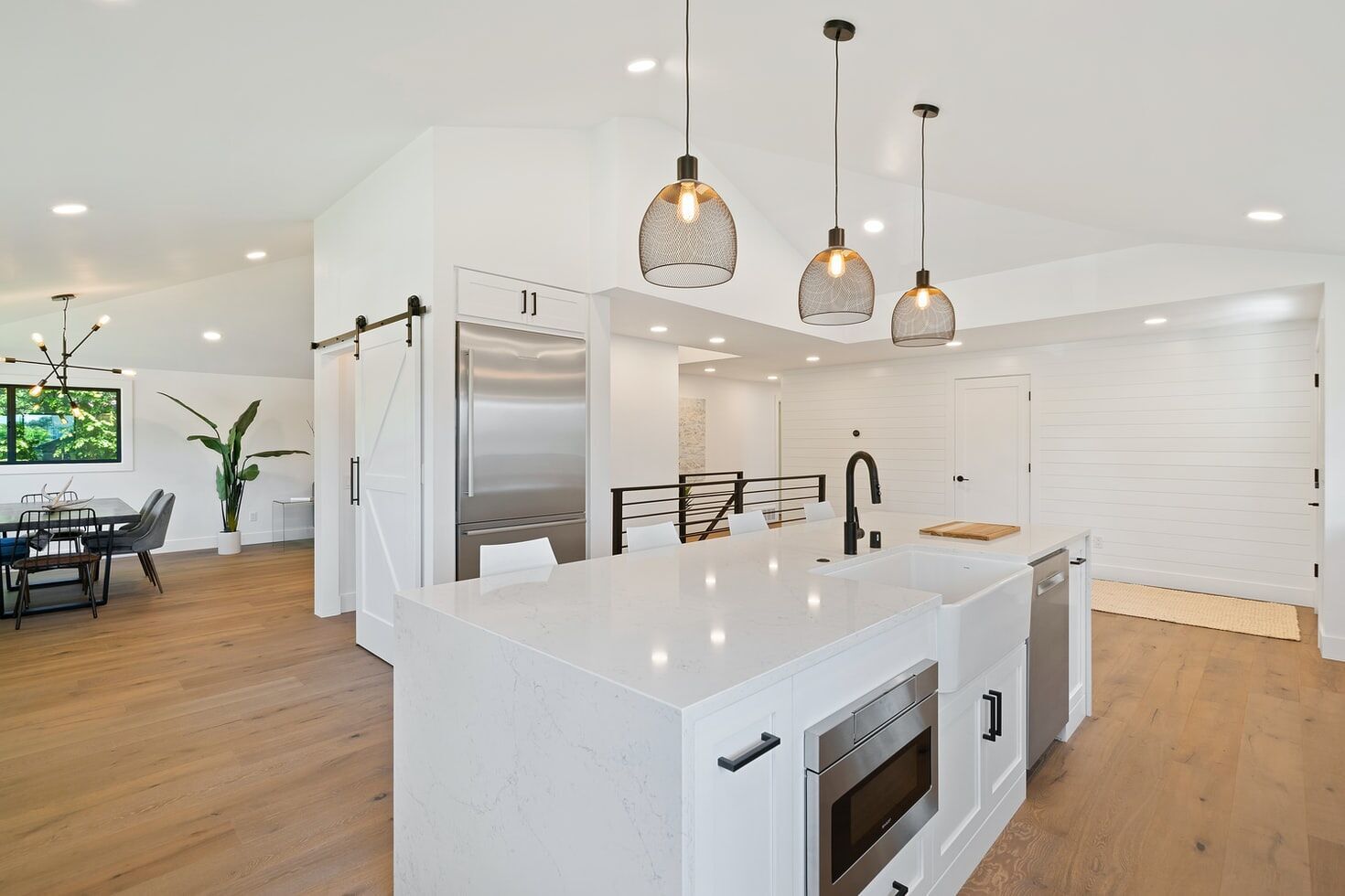 Modern kitchen with white quartz island, pendant lights, and wooden flooring