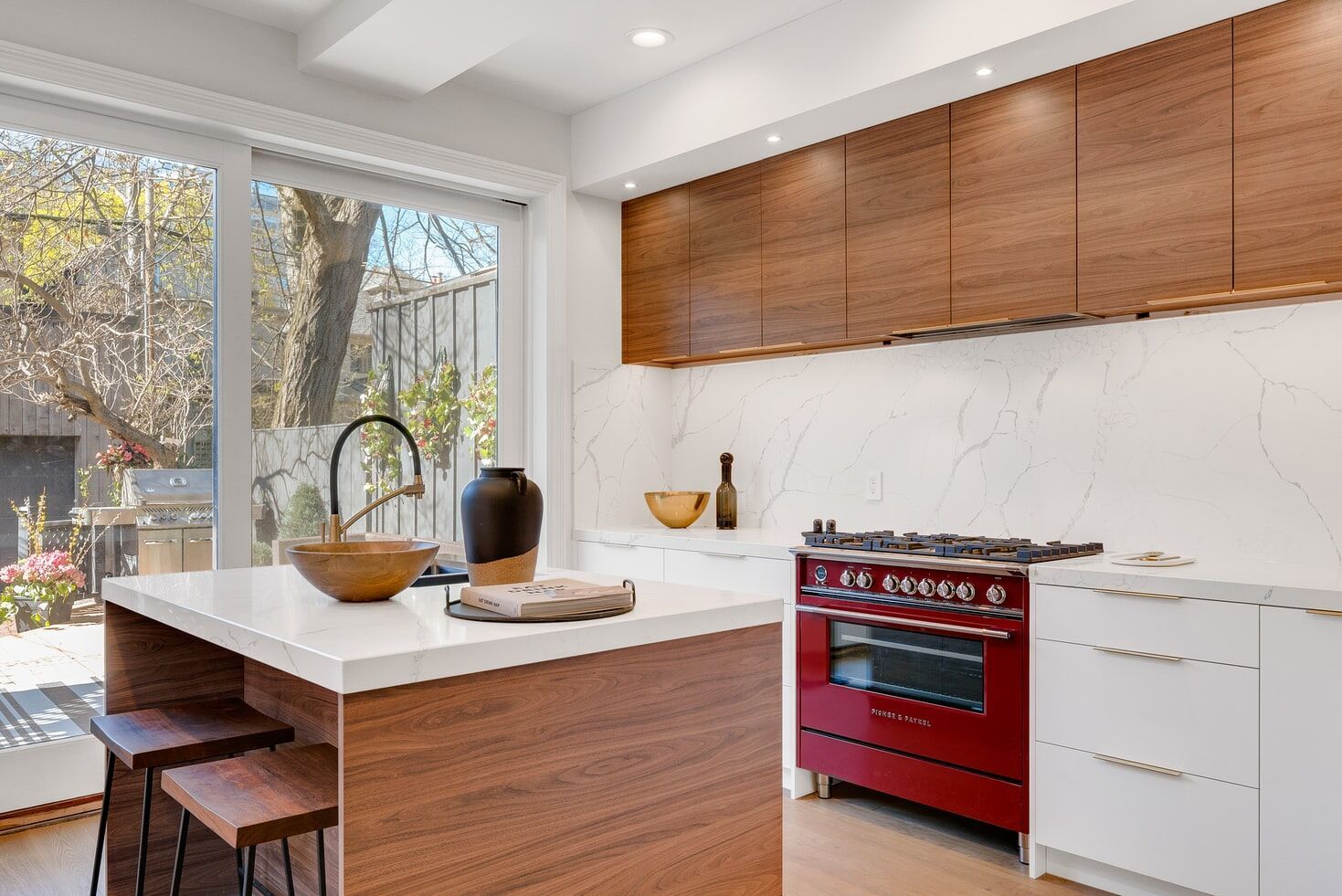 Modern kitchen with white marble backsplash, wooden island, and red oven
