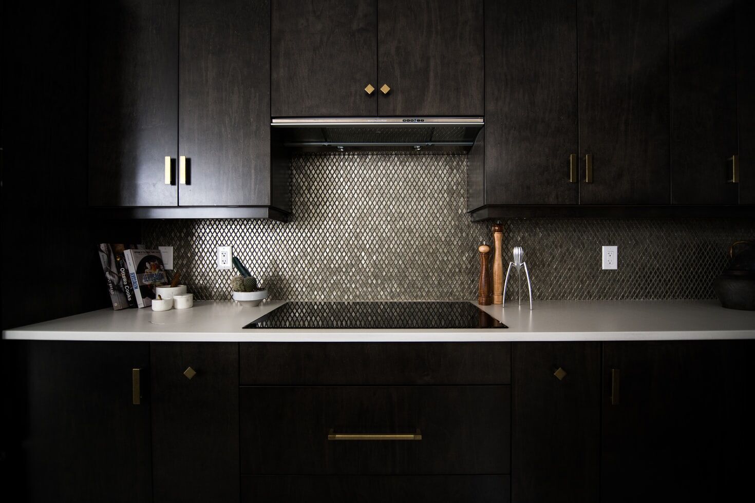 Modern kitchen featuring dark wood cabinets, a textured backsplash, and a white countertop with kitchen items