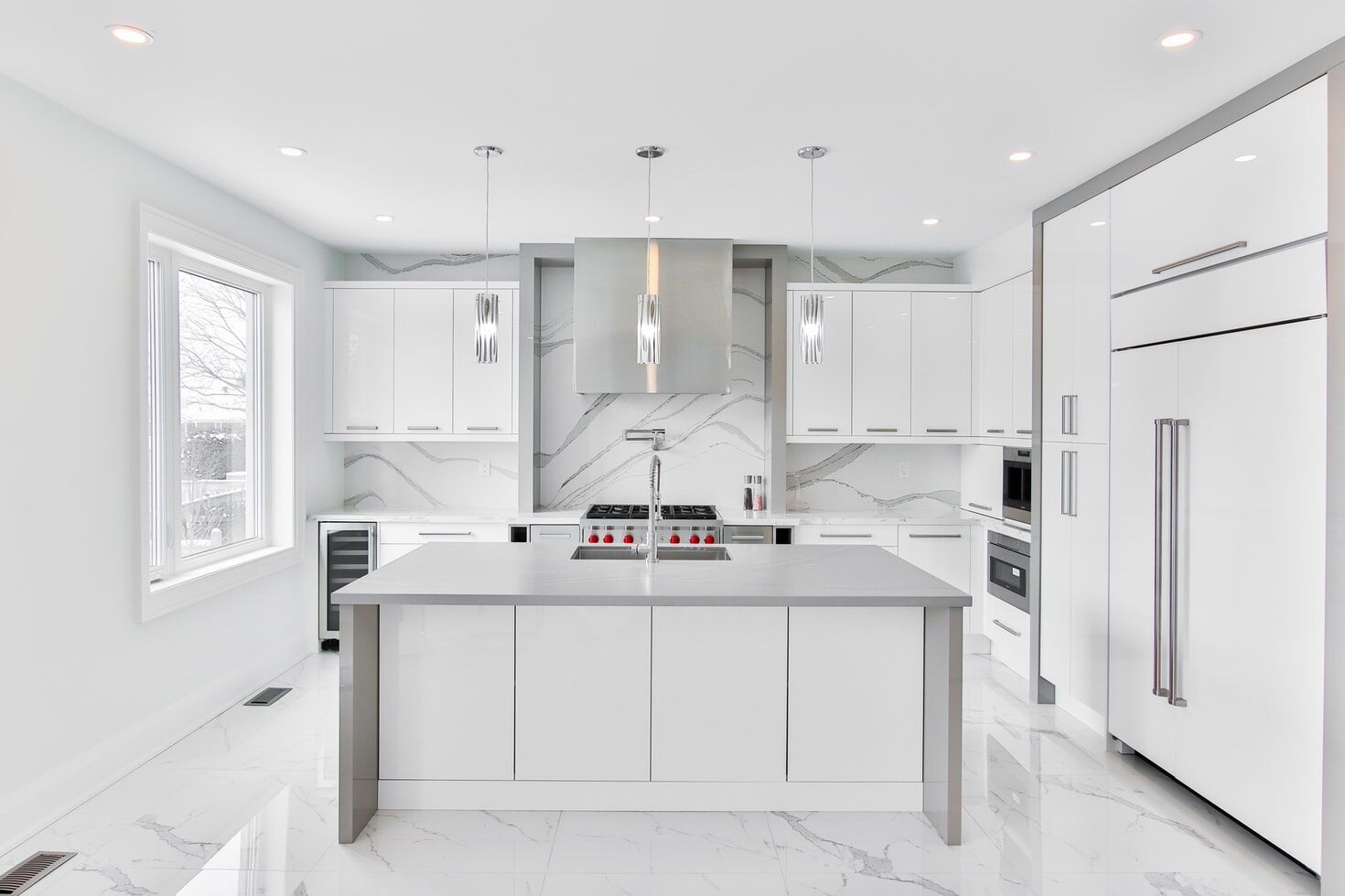 Modern white kitchen with marble countertops, island, and sleek cabinetry