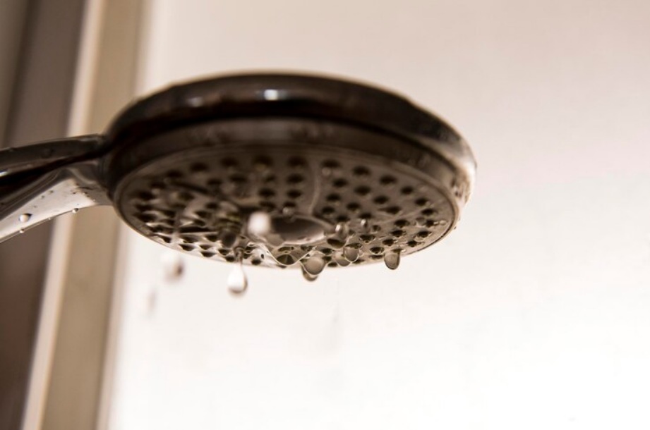 Close-up of a leaking showerhead with water droplets visible