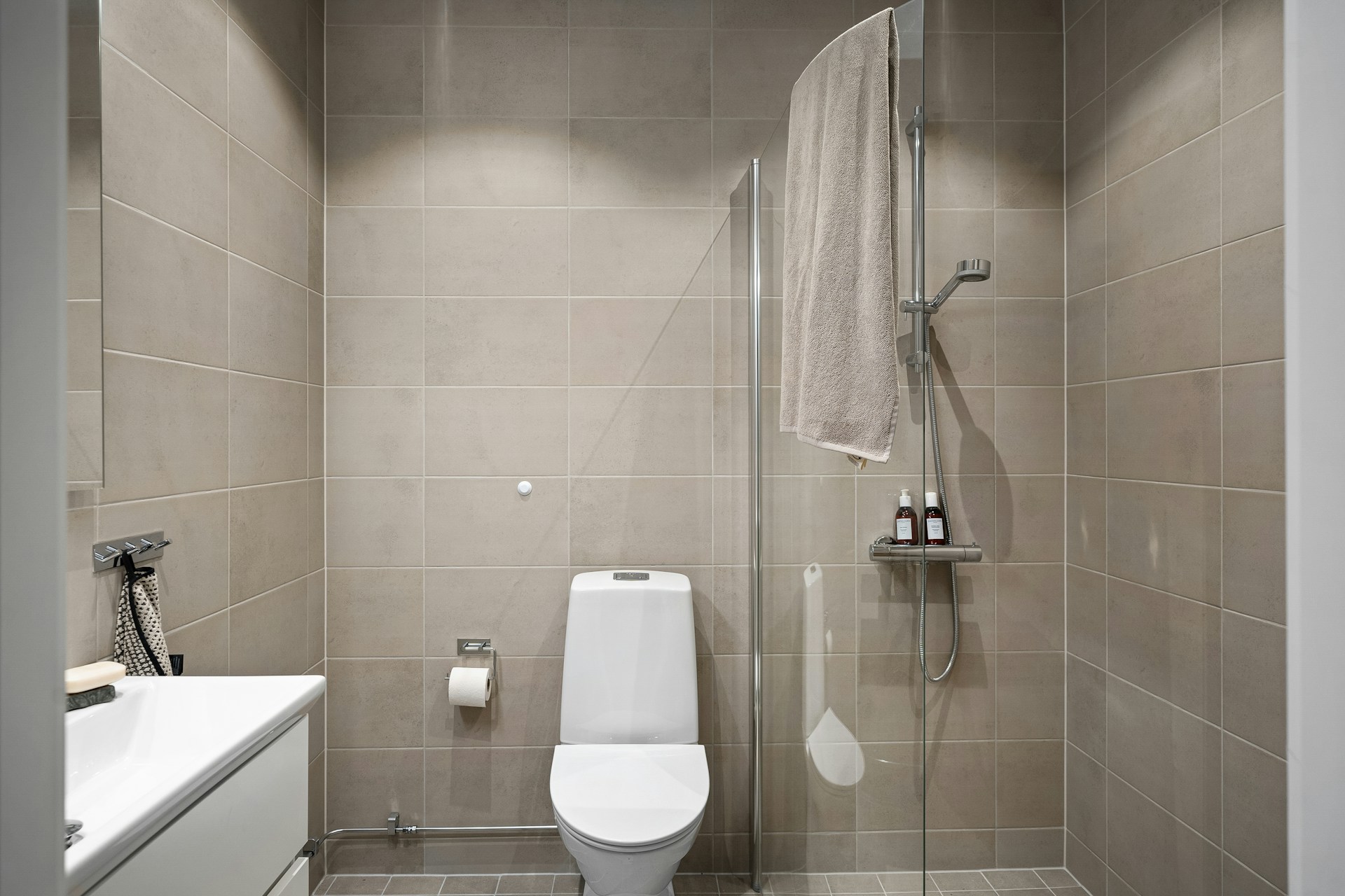 Bathroom with beige tiles, toilet, shower, and vanity with sink