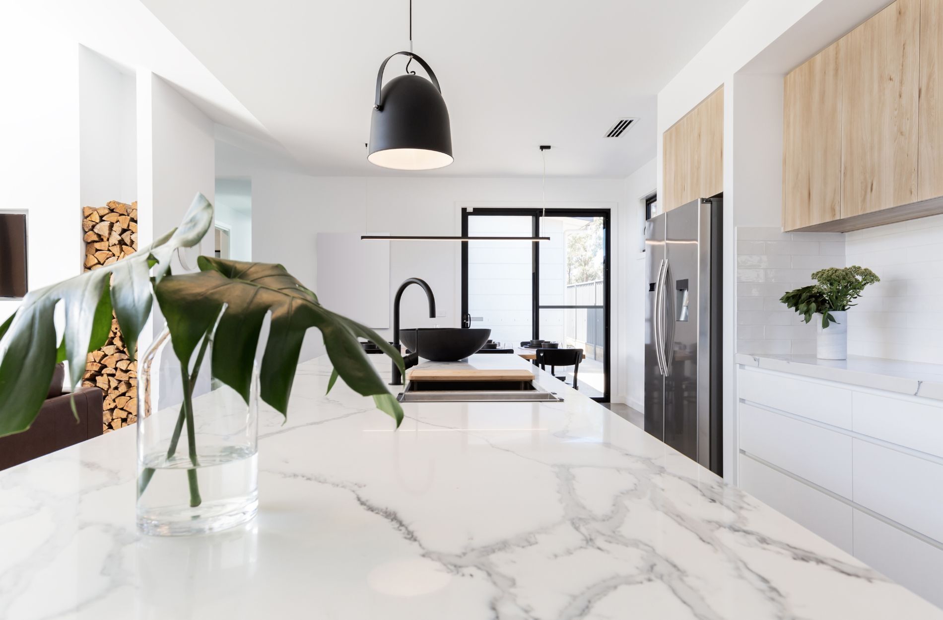 Modern kitchen with a polished white marble countertop, black pendant light, and wooden cabinets