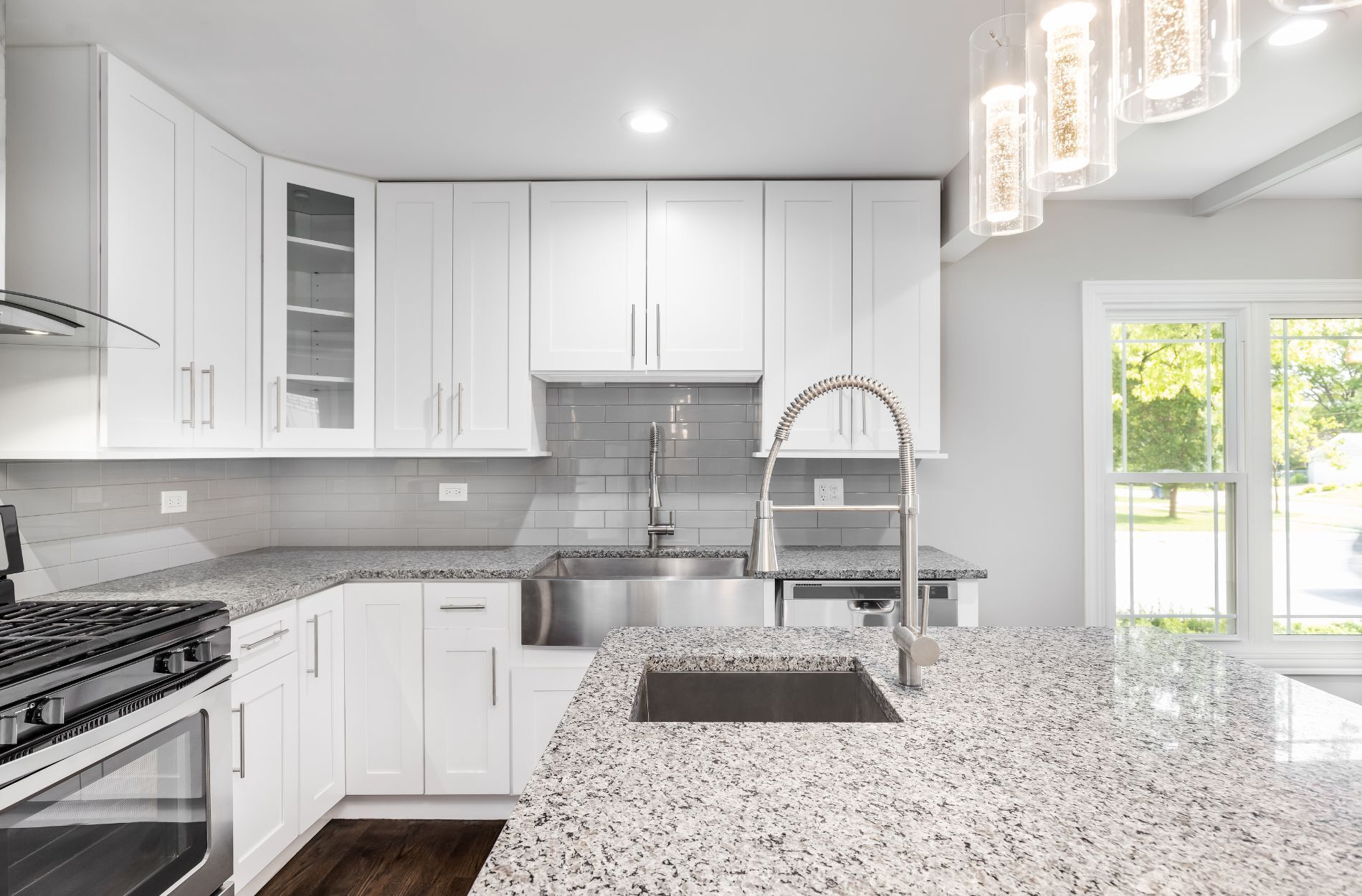 Modern kitchen with polished marble countertop, stainless steel sink, and white cabinets
