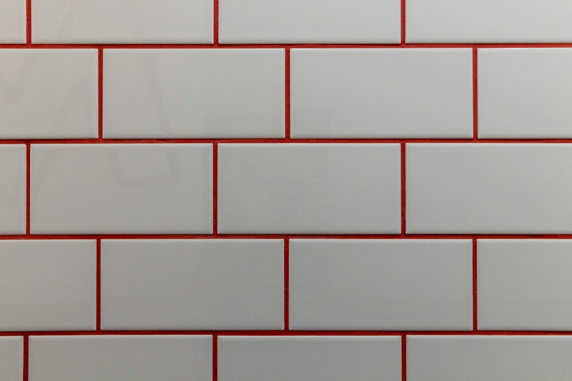 Close-up of white rectangular tiles with red grout in a subway pattern