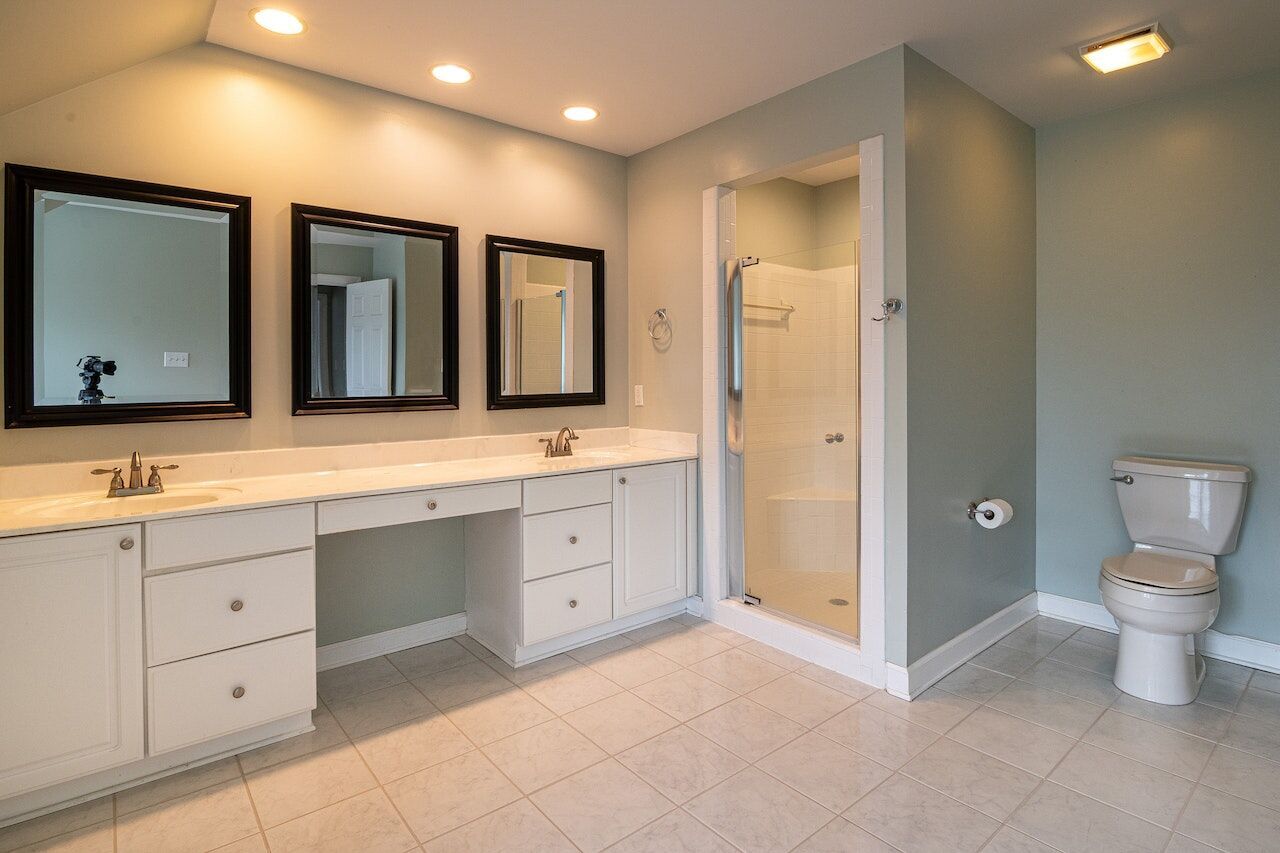 Bathroom with double vanity, glass shower, and tiled floor
