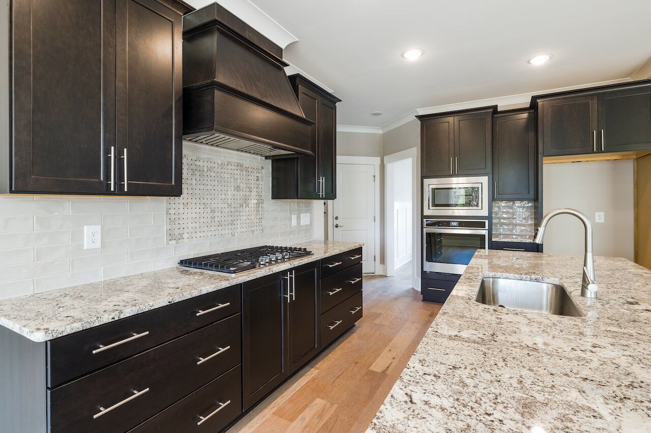 Modern kitchen with dark wood cabinets, granite countertop, and stainless steel sink