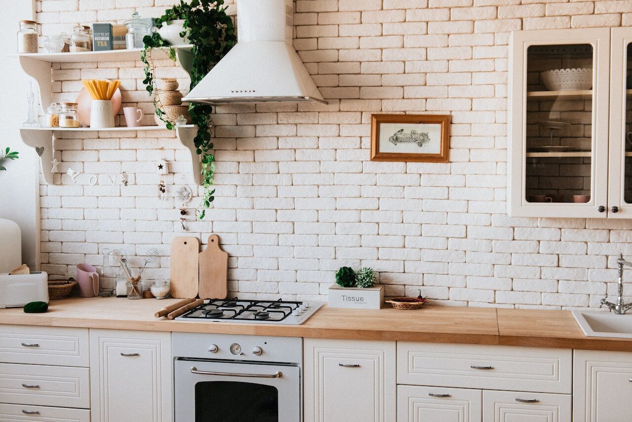 Cozy kitchen featuring white brick walls, wooden countertops, and open shelves with kitchen items