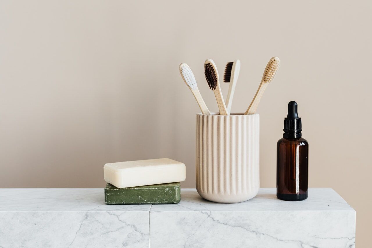 Marble surface with toothbrush holder, soap, and dropper bottle in a bathroom setting