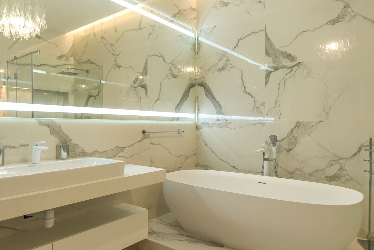 Modern bathroom with freestanding tub and marble walls, featuring a large vanity and mirror
