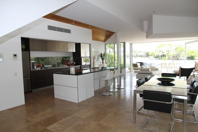 Open-plan kitchen with stone flooring, white island, and large windows