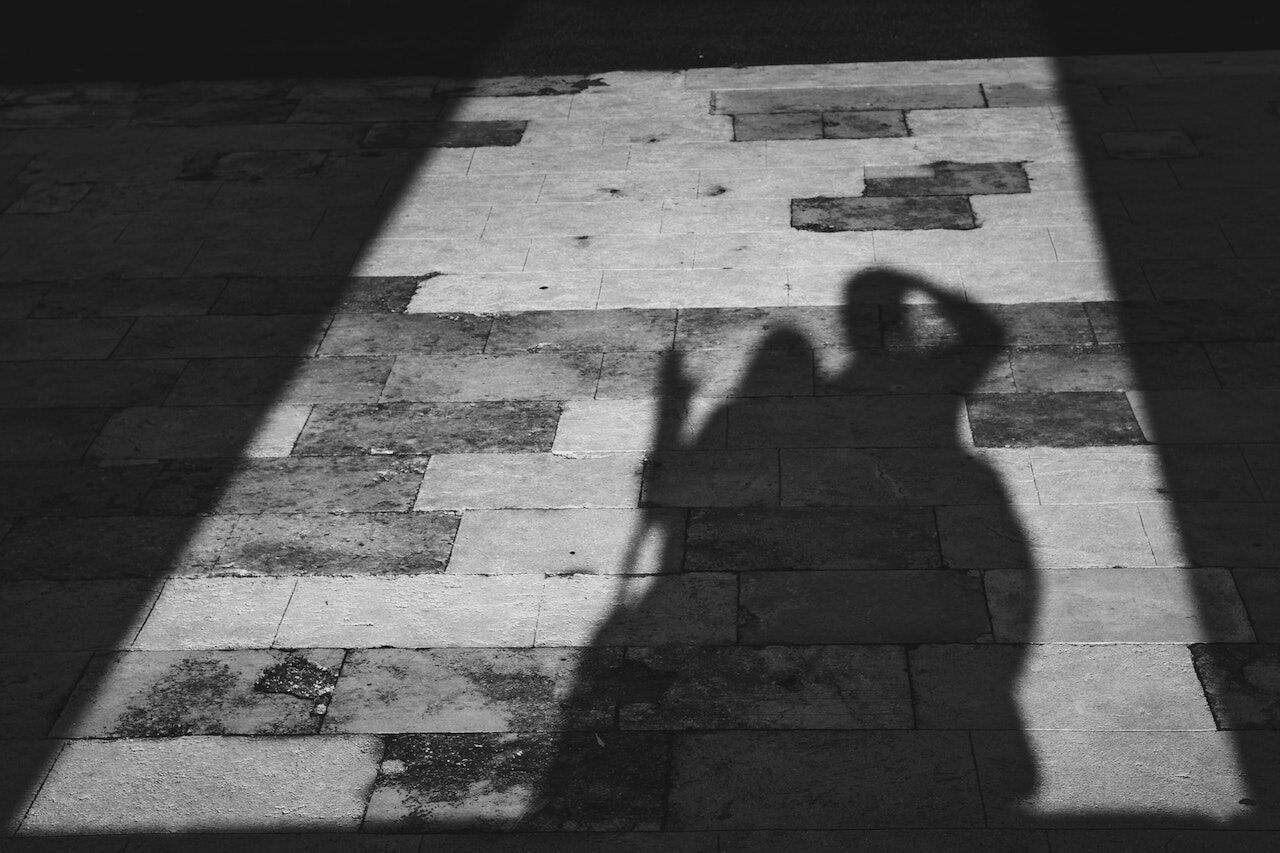 Black and white photo of a stone floor with two people's shadows