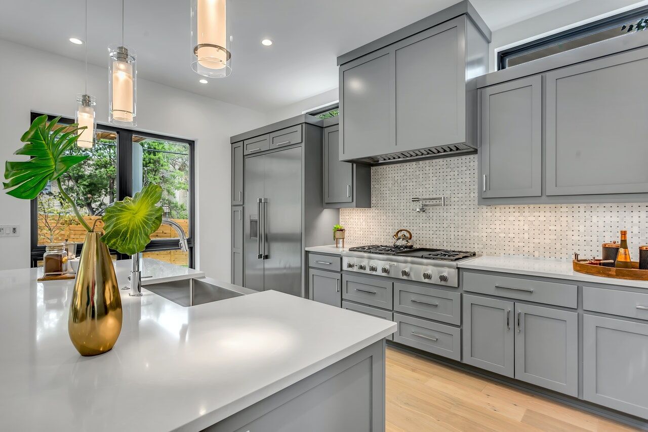 Modern kitchen with gray cabinets, white marble countertop, and mosaic tile backsplash