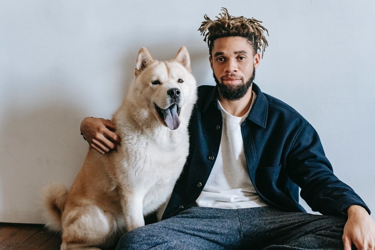 Man sitting on the floor with an Akita Inu dog beside him, both looking at the camera