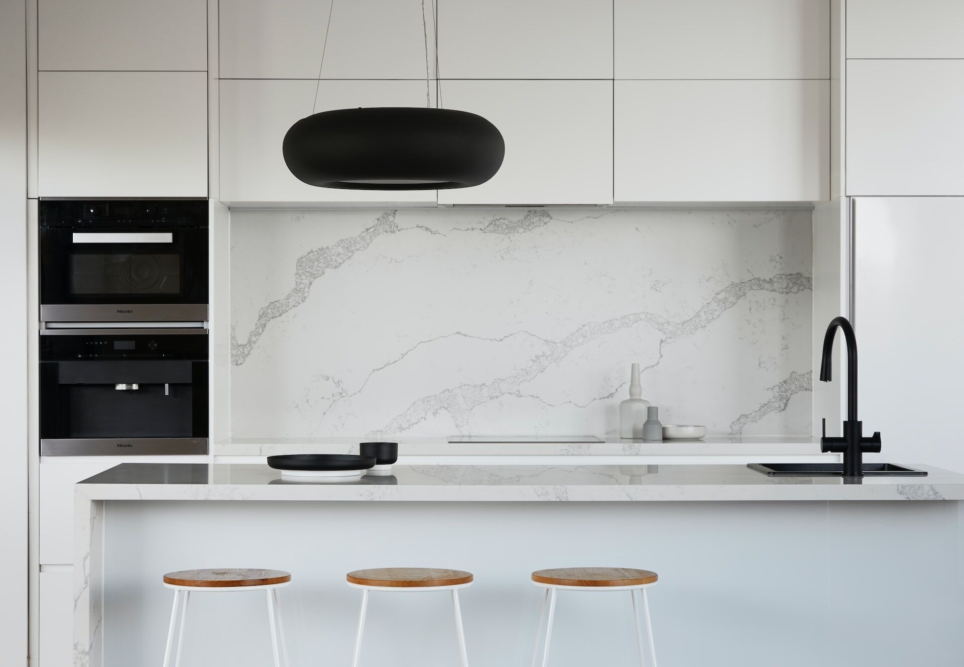 Modern kitchen with white cabinets, marble backsplash, and black fixtures