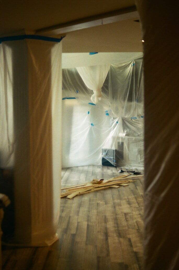 Room under renovation with plastic sheets and wooden planks on the floor