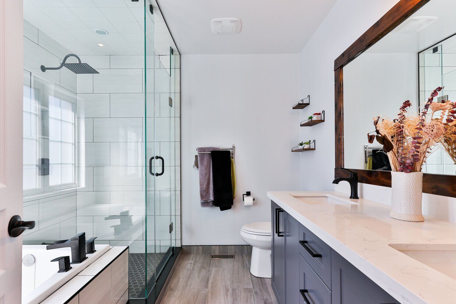 Modern bathroom with glass shower, double vanity, and freestanding bathtub