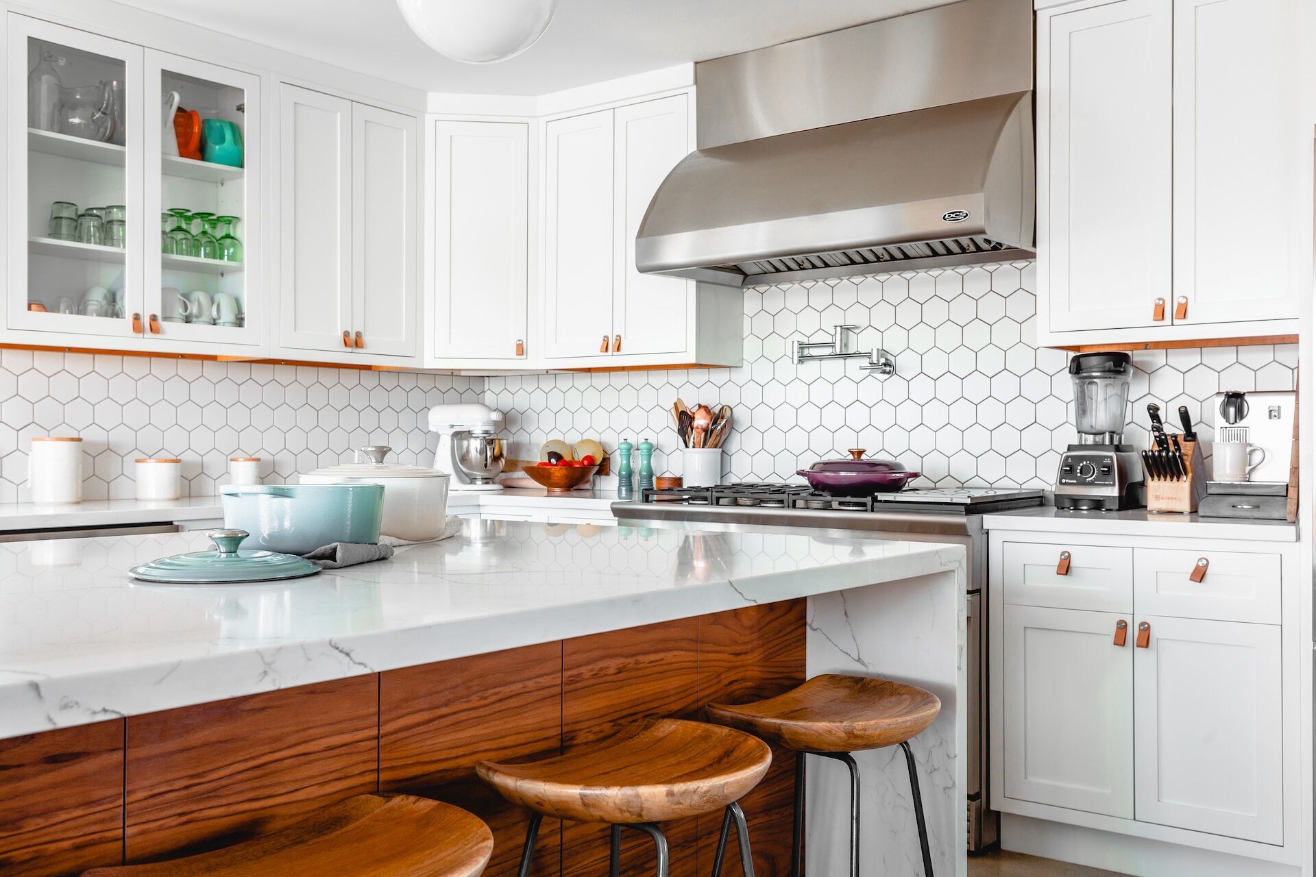 Modern kitchen with marble countertop, white cabinets, and hexagonal tile backsplash