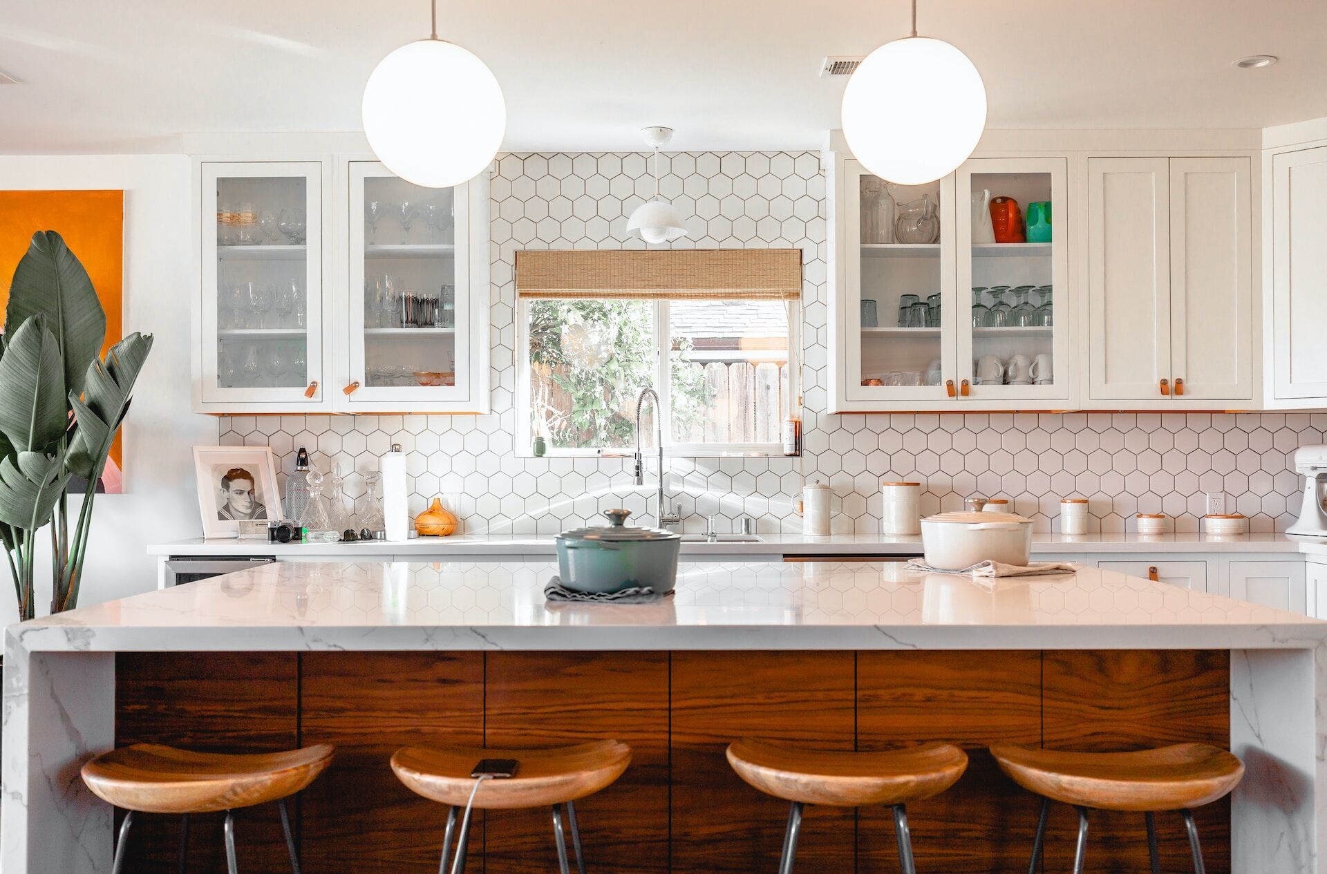 Modern kitchen featuring a marble island, hexagonal tile backsplash, and wooden stools