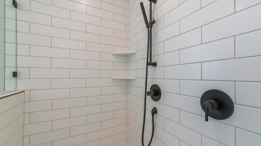 Shower with white subway tiles, dark fixtures, and corner shelves